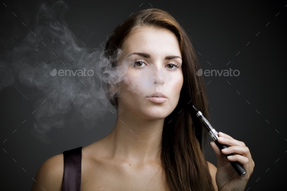 Elegant woman smoking e cigarette with smoke Stock Photo by